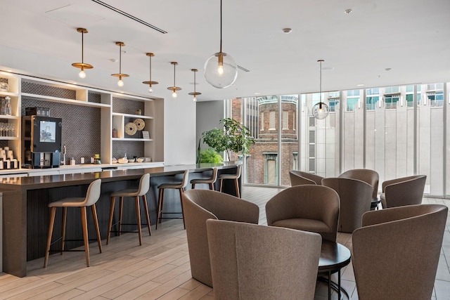 interior space featuring floor to ceiling windows, light wood finished floors, dark countertops, open floor plan, and a kitchen breakfast bar