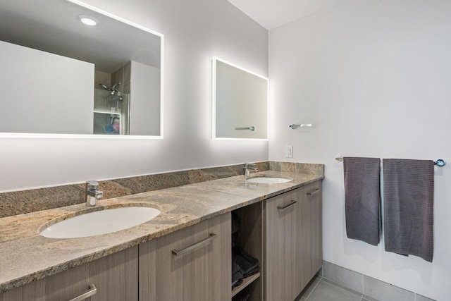 bathroom with a shower, tile patterned flooring, a sink, and double vanity