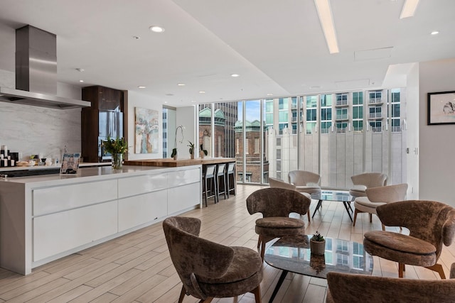 interior space with light wood-style flooring, white cabinetry, modern cabinets, a wall of windows, and extractor fan