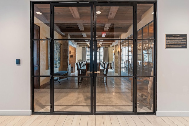 unfurnished dining area featuring baseboards, french doors, beam ceiling, and wood finished floors