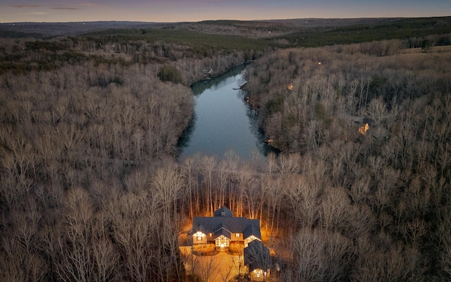 aerial view at dusk with a water view and a wooded view