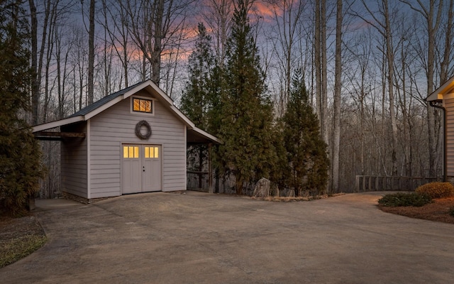 view of outbuilding with driveway, fence, and an outbuilding