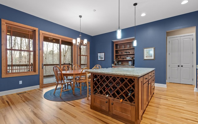 interior space with pendant lighting, recessed lighting, an inviting chandelier, light wood-type flooring, and baseboards