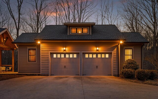 chalet / cabin with driveway, an attached garage, and roof with shingles