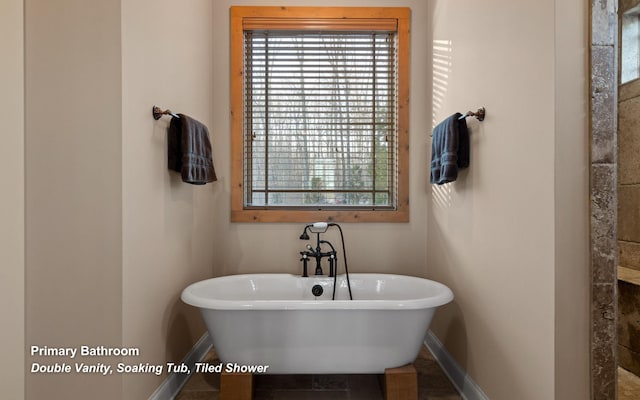 bathroom with a freestanding tub and baseboards