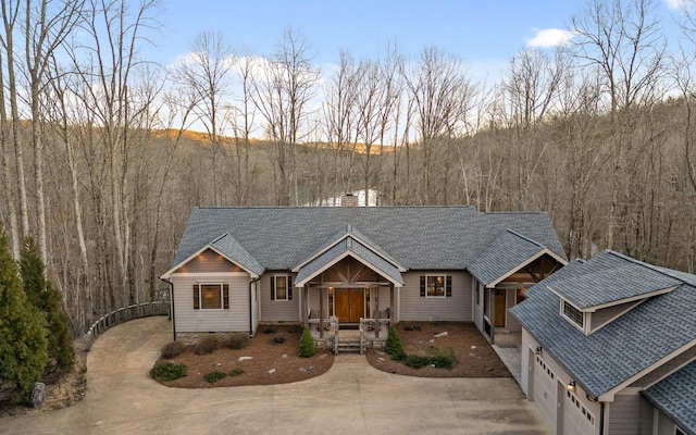 view of front facade with crawl space, a chimney, a wooded view, and roof with shingles