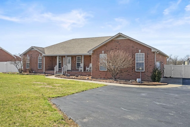 ranch-style home featuring an attached garage, brick siding, a front yard, and fence