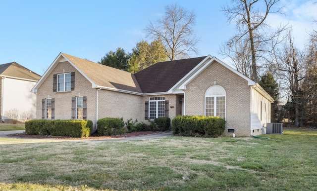 view of front of home with a front yard, central AC, and brick siding