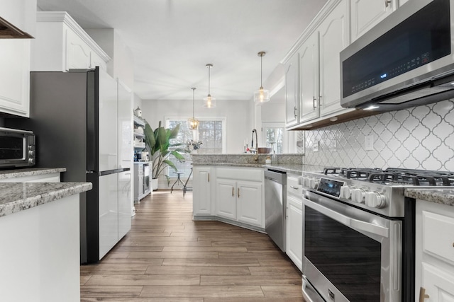 kitchen with white cabinetry, appliances with stainless steel finishes, decorative backsplash, and light wood-style flooring