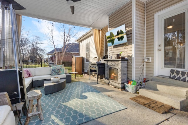 view of patio / terrace with entry steps, ceiling fan, a grill, fence, and an outdoor living space with a fireplace