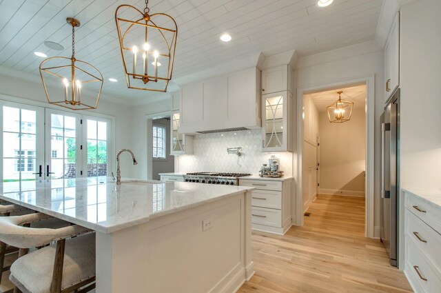 kitchen featuring a chandelier, backsplash, a sink, and white cabinets