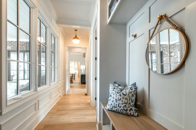 mudroom featuring crown molding, light wood-type flooring, and a decorative wall