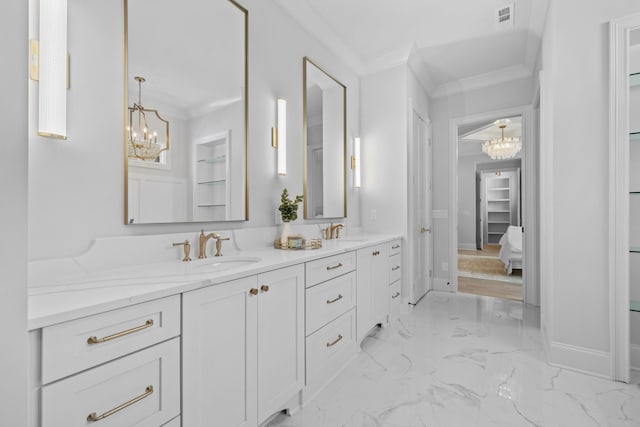 full bathroom featuring ornamental molding, marble finish floor, a sink, and an inviting chandelier