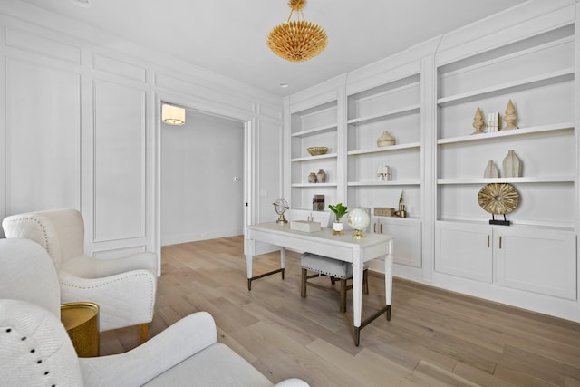 office space with built in shelves and light wood-type flooring