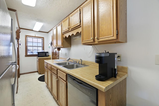 kitchen with light floors, light countertops, appliances with stainless steel finishes, a sink, and a textured ceiling