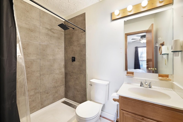 full bathroom with a textured ceiling, tiled shower, vanity, and toilet