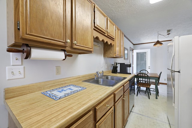 kitchen with light floors, light countertops, freestanding refrigerator, a sink, and a textured ceiling