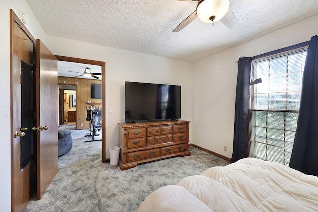 carpeted bedroom featuring baseboards, a ceiling fan, and a textured ceiling