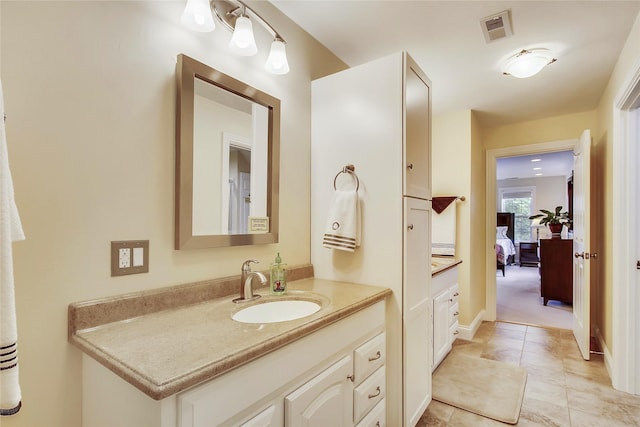 ensuite bathroom featuring visible vents, ensuite bathroom, vanity, tile patterned flooring, and baseboards