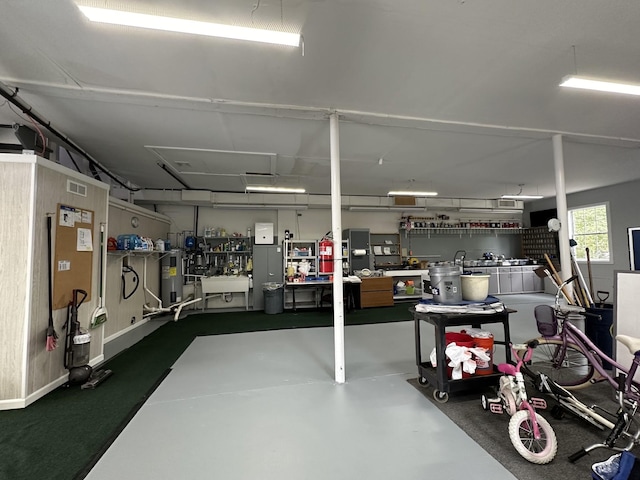 garage with electric water heater and visible vents