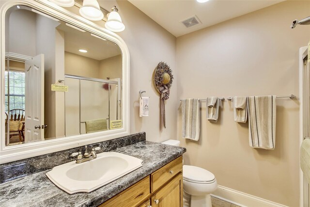 bathroom with visible vents, toilet, a stall shower, vanity, and baseboards