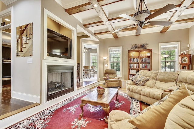 living area with beamed ceiling, a fireplace, coffered ceiling, and a ceiling fan