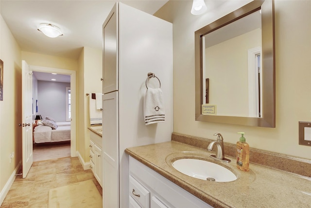 bathroom with ensuite bath, vanity, and baseboards