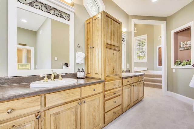 full bath with double vanity, baseboards, and a sink