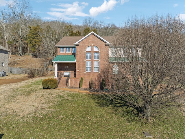 view of front of house with metal roof, brick siding, fence, a front lawn, and a standing seam roof