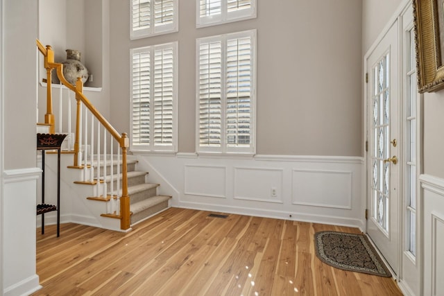 entrance foyer with stairs, visible vents, plenty of natural light, and hardwood / wood-style flooring