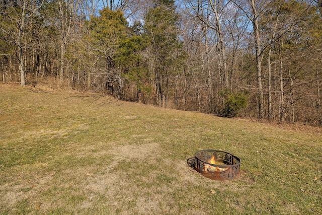 view of yard with an outdoor fire pit and a forest view