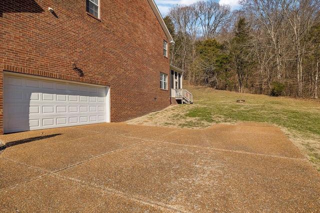 view of property exterior featuring driveway, a yard, a garage, and brick siding