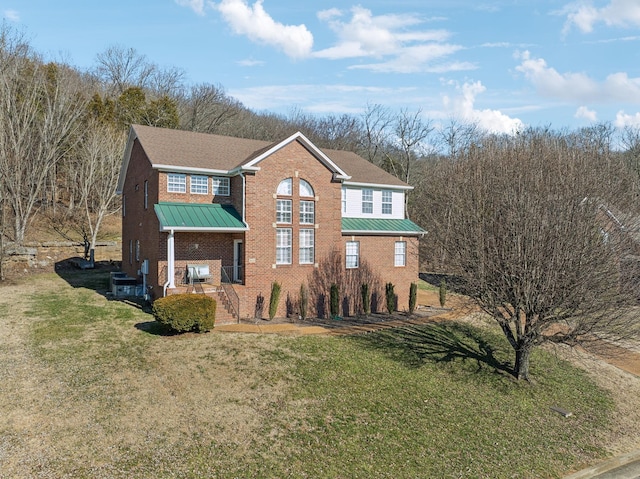 view of front of property with metal roof, brick siding, a standing seam roof, and a front lawn