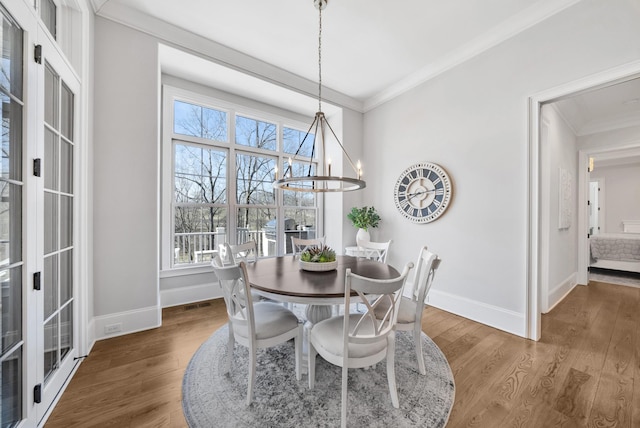 dining area featuring ornamental molding, a chandelier, baseboards, and wood finished floors