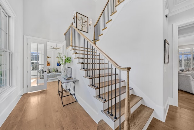 stairway with a high ceiling, baseboards, and wood finished floors