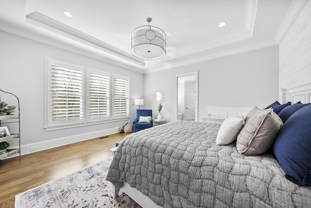 bedroom featuring recessed lighting, wood finished floors, baseboards, ornamental molding, and a tray ceiling