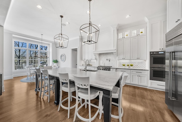 kitchen featuring a sink, white cabinets, appliances with stainless steel finishes, custom exhaust hood, and backsplash