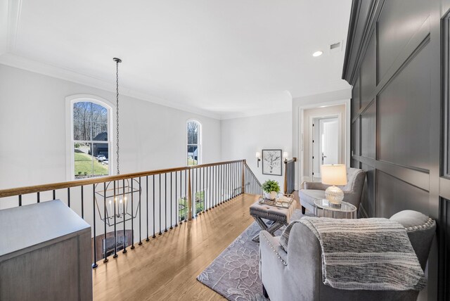 sitting room featuring ornamental molding, light wood-style flooring, visible vents, and a wealth of natural light