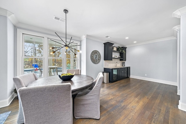 dining space with wet bar, visible vents, dark wood-type flooring, and ornamental molding