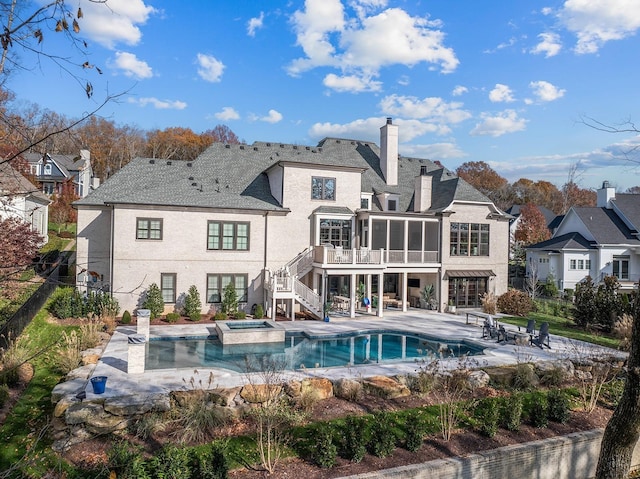 back of house with a sunroom, a chimney, stairs, fence, and a patio area