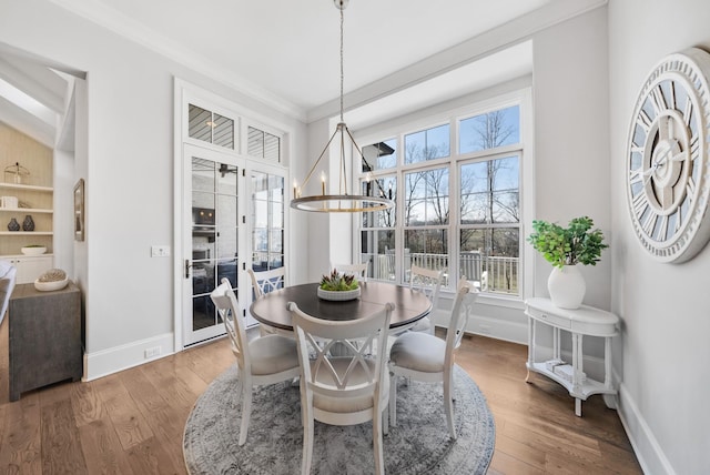 dining space with a wealth of natural light, a notable chandelier, ornamental molding, and wood finished floors