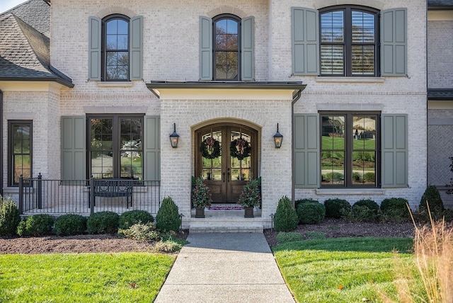 doorway to property with a porch, french doors, and brick siding