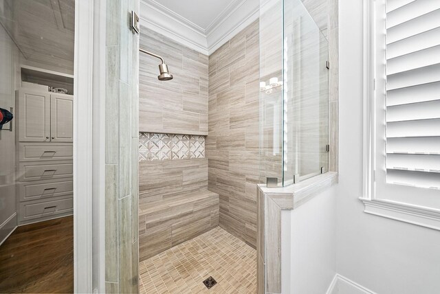 bathroom with ornamental molding, a tile shower, and wood finished floors