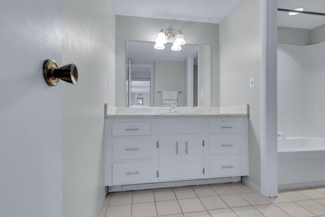 bathroom featuring baseboards, vanity, a bathtub, and tile patterned floors