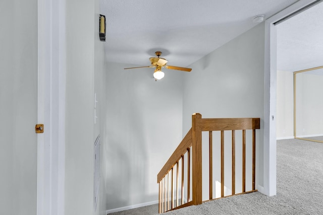 stairway featuring ceiling fan, baseboards, and carpet flooring