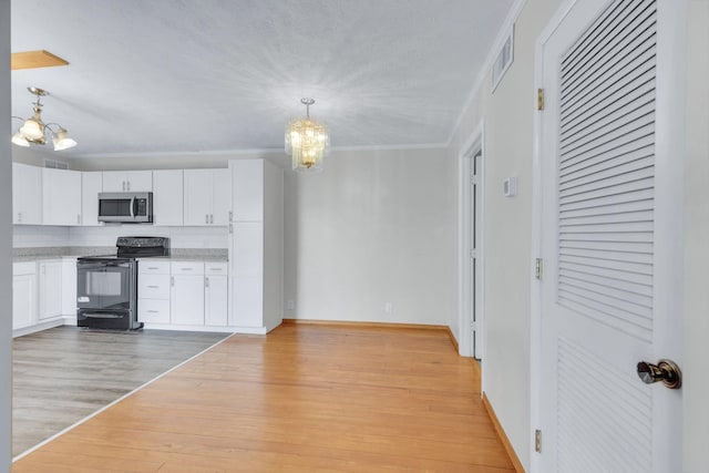 kitchen with stainless steel microwave, a notable chandelier, light wood finished floors, and black / electric stove