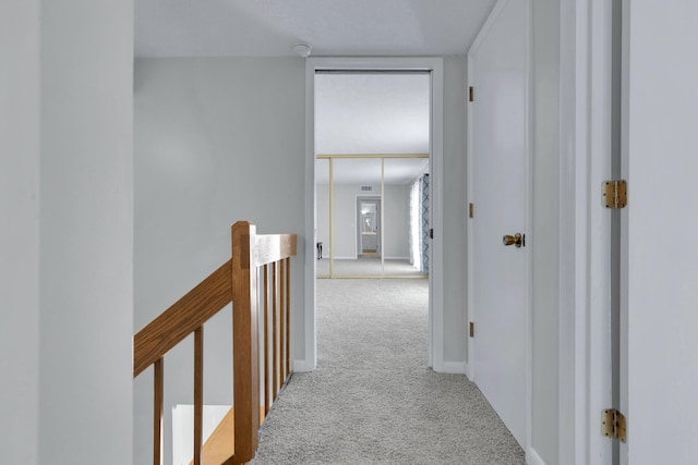 corridor with carpet flooring, an upstairs landing, and baseboards