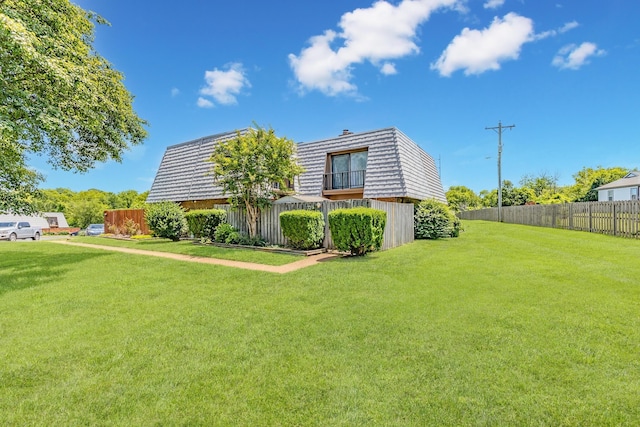 exterior space with a yard, mansard roof, and fence