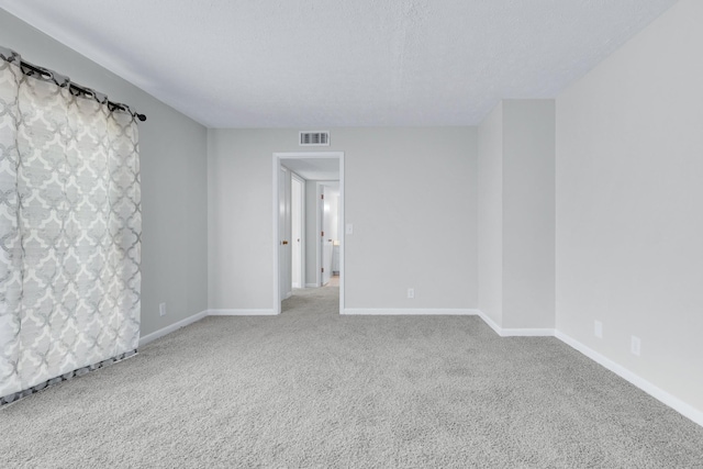 carpeted empty room featuring visible vents, a textured ceiling, and baseboards