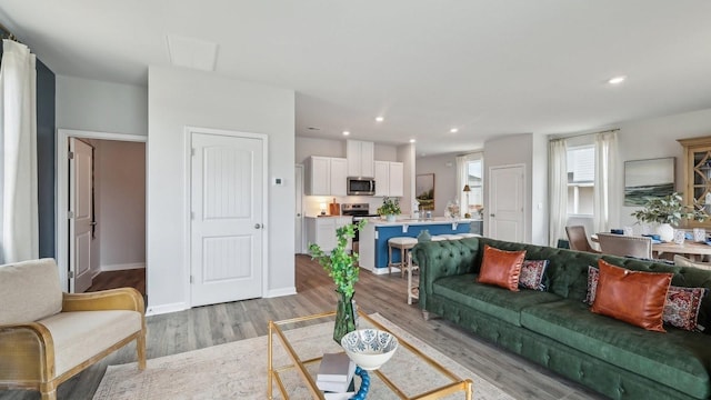 living room featuring baseboards, recessed lighting, and light wood-style floors